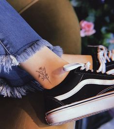 a woman's foot with a small flower tattoo on it