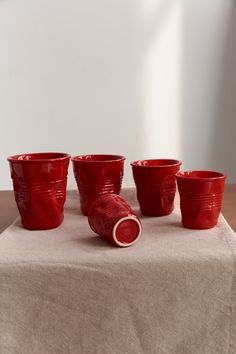 four red cups sitting on top of a white table cloth next to a cup holder