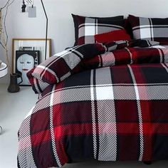 a bed with red and black plaid comforter in a bedroom next to a window