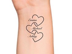 two hearts tattoo on the wrist with names written in black ink, and one heart is shown