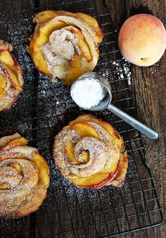 several pastries on a cooling rack with powdered sugar and an apple in the background