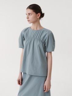 This is a clean and casual blouse by EAAH that is made out of high quality and sturdy fabric. With unique design detail and trendy mood, you can style it for your refined and casual daily outfit.- Set up matching skirt- Loop button closure on the back- High quality sea shell buttons- Shirring detail and roune neckline Modern Solid Color Blouse For Spring, Modern Blouse For Spring, Modern Blue Tops For Daywear, Gray Cotton Blouse For Summer, Spring Gray Blouse For Office, Gray Blouse For Office In Spring, Gray Relaxed Fit Cotton Blouse, Spring Gray Office Blouse, Versatile Solid Cotton Blouse