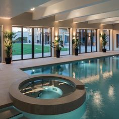 an indoor swimming pool surrounded by lounge chairs and large sliding glass doors leading to the outside