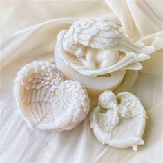 three white angel figurines sitting next to each other on a tablecloth covered surface