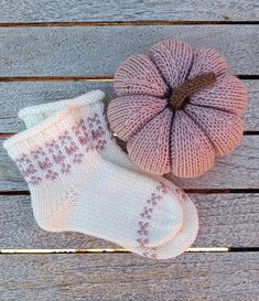 two knitted socks and a ball of yarn sitting on a wooden surface next to each other