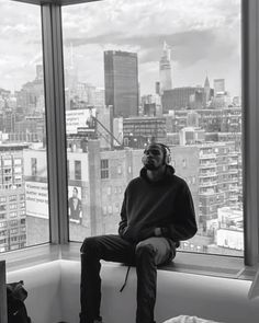 a man sitting on top of a window sill in front of a cityscape