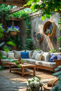 an outdoor living area with couches, tables and potted plants on the wall