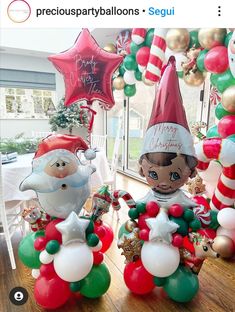 some balloons and decorations are on the table in front of a window with santa clause