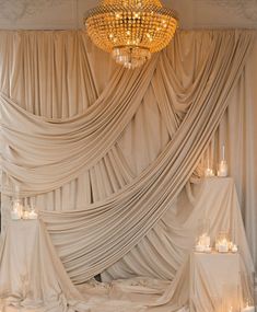 a room that has some lights on the ceiling and drapes around it with candles