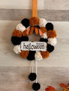 a halloween wreath with pom - poms hanging from it