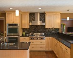 a modern kitchen with stainless steel appliances and wood cabinets, along with black counter tops