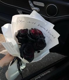 a bouquet of roses is held in front of the door of a car with an inscription on it