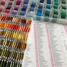 several rows of different colored threads in plastic containers next to each other on a table