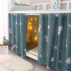 a child's bed with curtains and lights in the corner, next to a stuffed animal