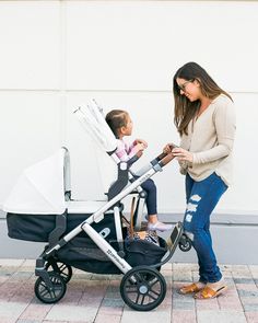 a woman standing next to a baby in a stroller