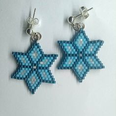 two small blue and white stars are hanging from silver earwires