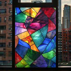 a colorful stained glass window with buildings in the backgroung and skyscrapers behind it