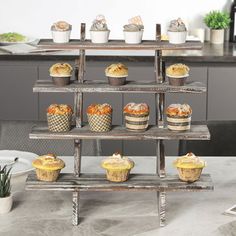 an assortment of cupcakes and muffins on a wooden stand in a kitchen