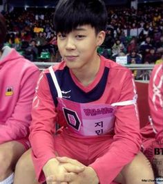 a young man sitting on top of a bench in front of a crowd wearing pink uniforms