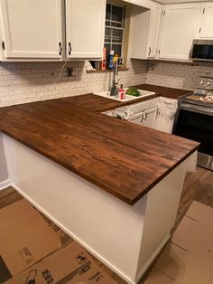 a kitchen with white cabinets and wood counter tops in the process of remodeling