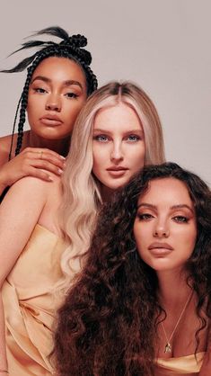 three women with long hair and braids posing for a magazine cover photo together, one woman is wearing a yellow dress