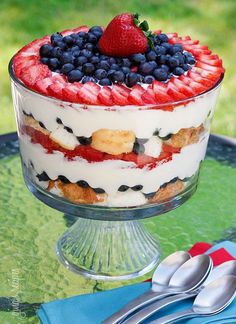 there are two desserts on the table and one is decorated with strawberries, blueberries, raspberries