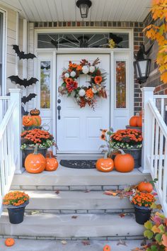 a front porch decorated for halloween with pumpkins and flowers