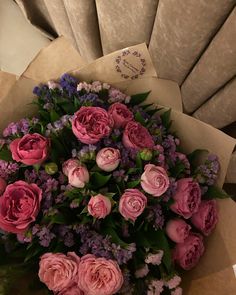 a bouquet of pink and purple flowers sitting on top of a brown paper wrapper