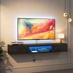 a flat screen tv sitting on top of a wooden shelf next to a plant and lamp