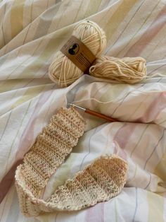 two skeins of yarn are laying on a bed next to some knitting needles