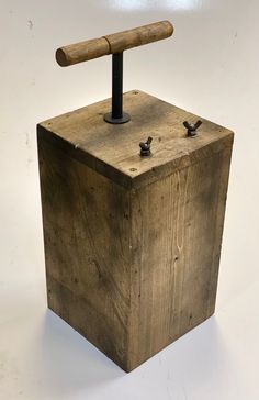 a wooden box with a hammer sticking out of it's top and two nails stuck in the middle