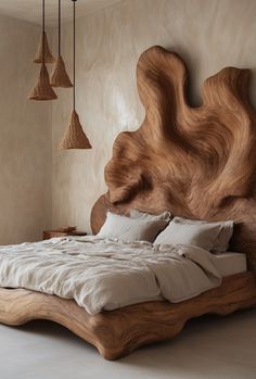 a bed with wooden headboard and pillows in a room that has beige walls, flooring and lamps hanging from the ceiling