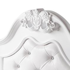 a white bed with an ornate headboard and buttons on the top of it's frame