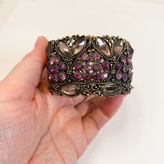 "Lovely vintage cuff style bracelet featuring 10 round purple rhinestone beads within a bronzed metallic heart and lavender Nanette rhinestones filling in the empty spaces with two at the bottom on the diagonal and one at the top on the horizontal. Giving lovely pink and purple tones, this wonderful bracelet would make an awesome gift for the person in your life who loves a little vintage bling and is appropriate for all ages. IMPERFECTIONS: Good vintage condition, commiserate with age. MISSING ONE PURPLE ROUND RHINESTONE BEAD. See last image and zoom in. Please review photos and video closely as they are part of the description. Measurements Diameter 2.5\"  Width of Band 1.5\" If you like this item, please review the other items in my shop, I can combine shipping. https://www.etsy.com/sho Metal Jeweled Cuff Bracelet As Gift, Purple Rhinestone Bracelets Perfect For Gifts, Purple Rhinestone Bracelets As Gift, Vintage Purple Bracelets For Wedding, Jeweled Metal Cuff Bracelet - Gift, Adjustable Purple Bracelets With Rhinestones, Purple Rhinestone Bracelets For Gifts, Adjustable Purple Rhinestone Bracelets, Vintage Purple Jewelry With Rhinestones