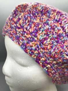 a white mannequin head wearing a multicolored knitted beanie hat