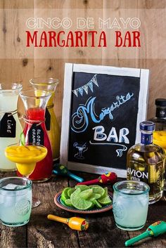 various drinks are sitting on a table next to a chalkboard with the words cinco de mayo margarita bar