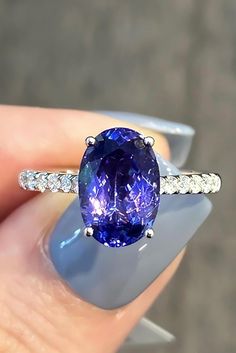 a close up of a person holding a ring with a large blue stone in it