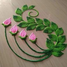 some green and pink flowers on a wooden table with leaves around it's edges