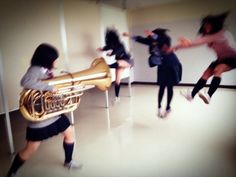 a group of young people playing musical instruments in a room with white walls and flooring