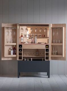 an open cabinet filled with wine glasses and liquor bottles next to a bar counter top