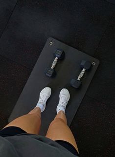 a person standing on top of a black mat with dumbbells