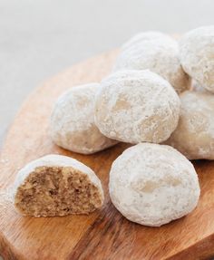 a wooden cutting board topped with snowball cookies