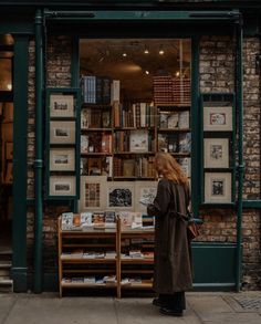 a woman standing in front of a book store looking at the books on the shelves