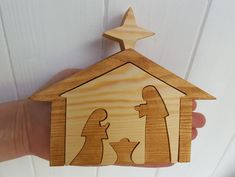 a wooden nativity ornament depicting the birth of jesus and mary, with a star on top