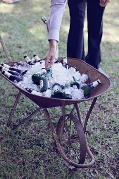 a wheelbarrow filled with lots of bottles and ice cubes on the grass