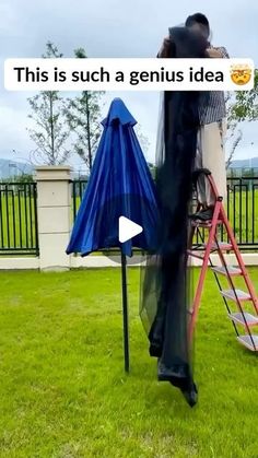 a man standing on top of a ladder next to a blue umbrella and another person