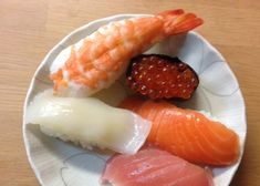 a plate with sushi and cauliflower on it sitting on a wooden table