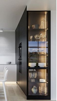 an open cabinet with glass doors in a kitchen next to a dining room table and chairs