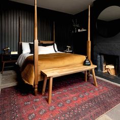 a bed sitting on top of a red rug next to a fire place in a bedroom