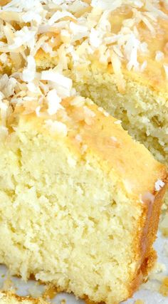 a close up of a cake with coconut toppings on a white plate and one slice cut from it